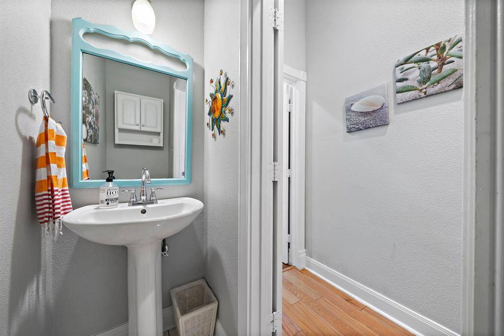 A cheerful half bathroom with pedestal sink, colorful mirror, and fun coastal décor—perfectly placed for guests.
