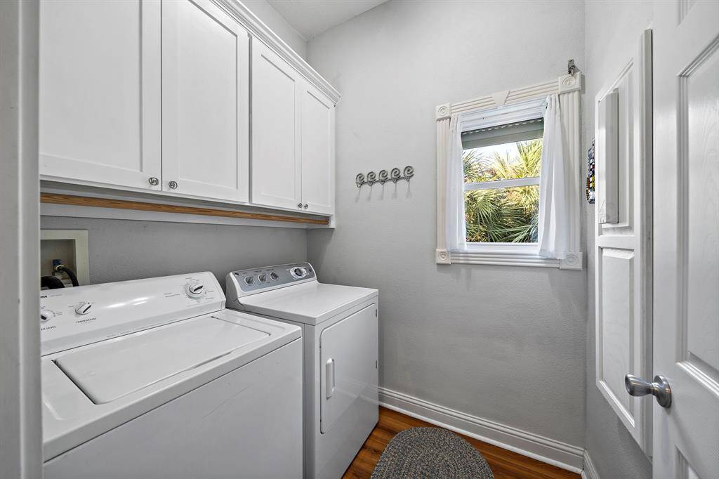 This bright and functional laundry room features upper cabinetry for storage, a full-size washer and dryer, and a window that brings in natural light. For added convenience, a laundry chute from the primary closet makes everyday tasks even easier.