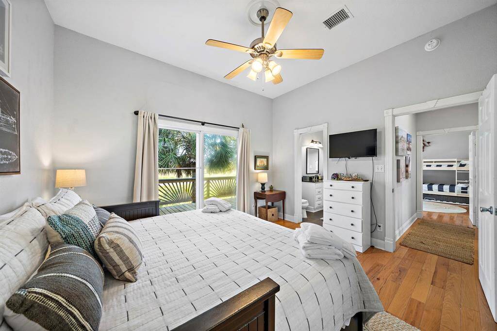 Bright and comfortable, this guest bedroom features deck access, a wall-mounted TV, and a serene color palette. It shares a Jack and Jill bathroom with the connected bunk room—ideal for hosting family or friends with ease.