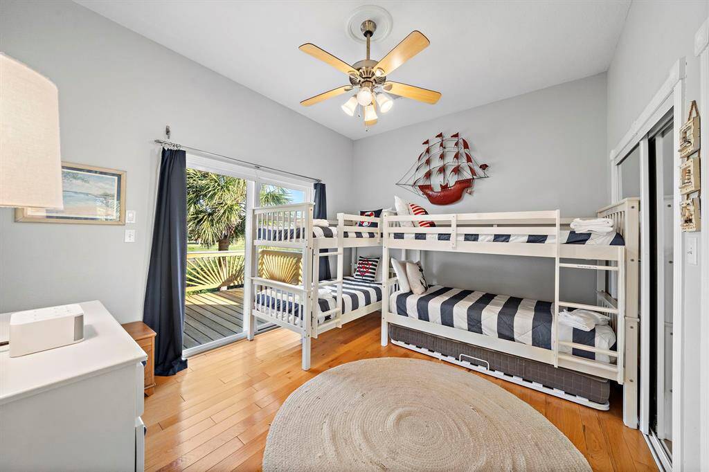 This cheerful guest bunk room is perfect for younger guests or additional sleeping space, featuring two twin-over-twin bunk beds and coastal décor. Sliding doors lead directly to the deck, while a Jack and Jill bathroom connects to the adjacent guest room.