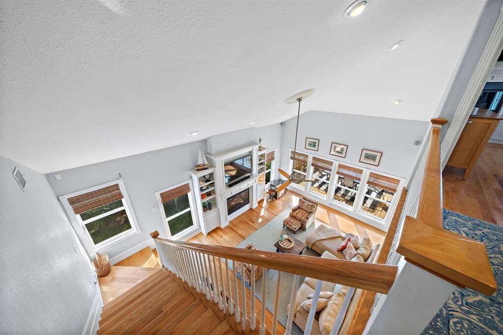 A stunning bird’s-eye perspective of the living area showcases the soaring ceilings, grand fireplace, and full wall of windows. This view highlights the bright and open design that defines the heart of this home