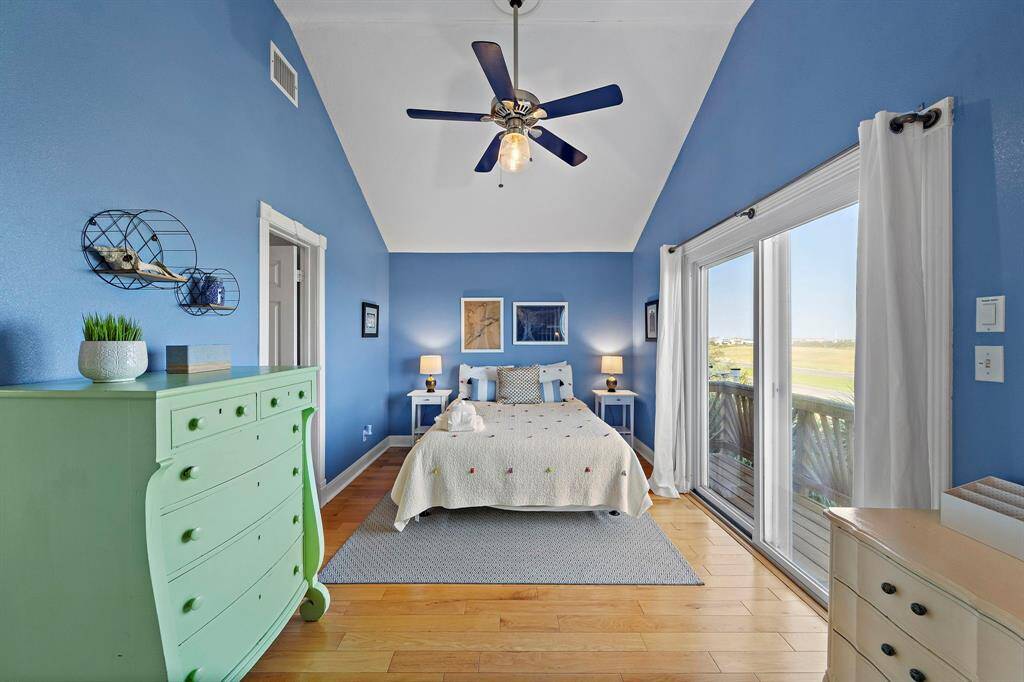 The tranquil blue walls and vaulted ceiling create a peaceful retreat in this upstairs bedroom, complete with private balcony access and scenic views.
