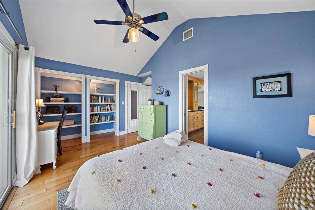 This serene upstairs bedroom features built-in bookshelves and a reading nook, along with sliding glass doors leading out to a private balcony.