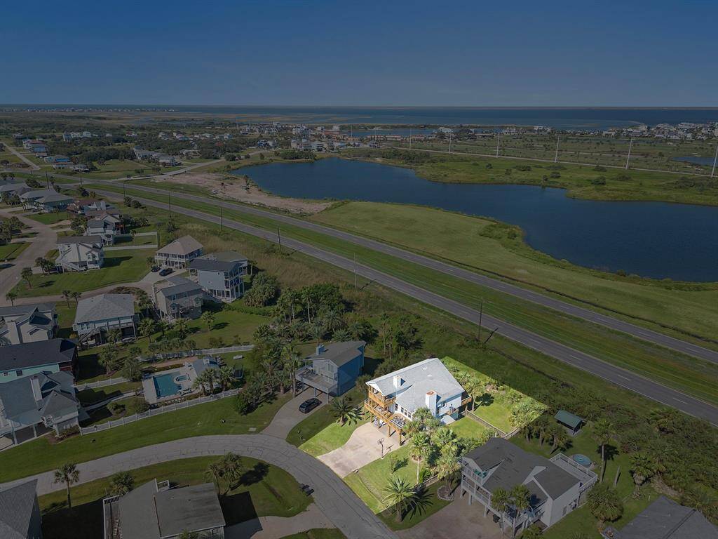 Aerial view with property boundary highlighted, showcasing the home’s spacious lot, mature palms, and prime location near both the beach and bay.