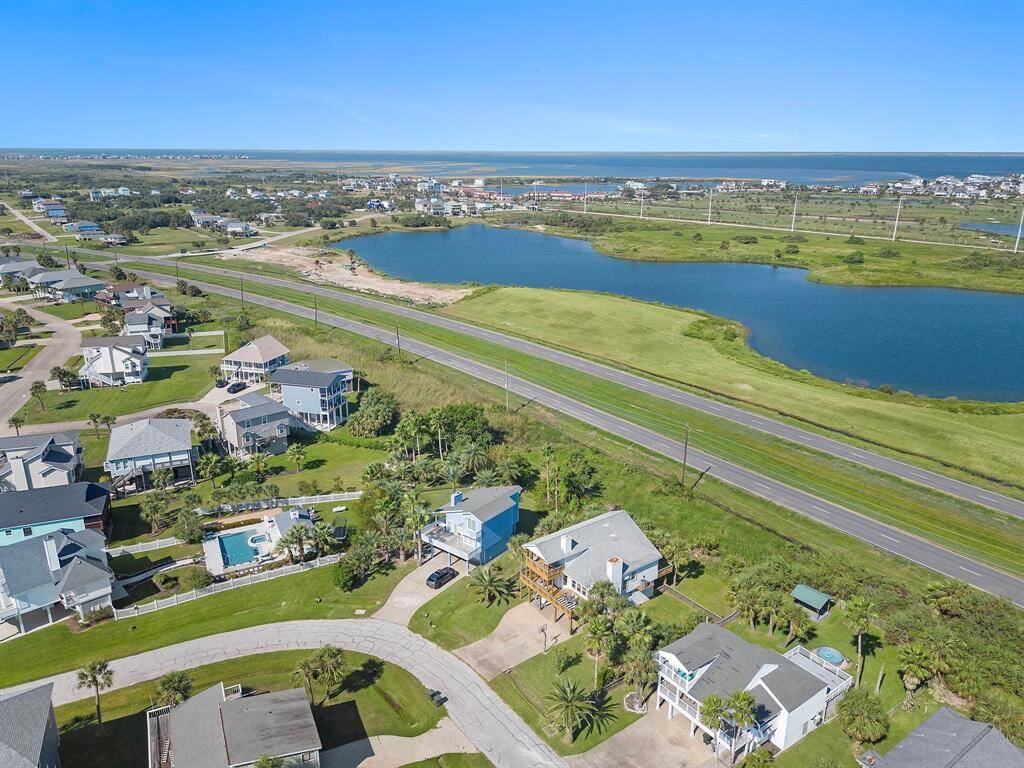 A wider aerial capture of the home without highlight, illustrating its placement on a quiet cul-de-sac with ample green space and scenic surroundings.