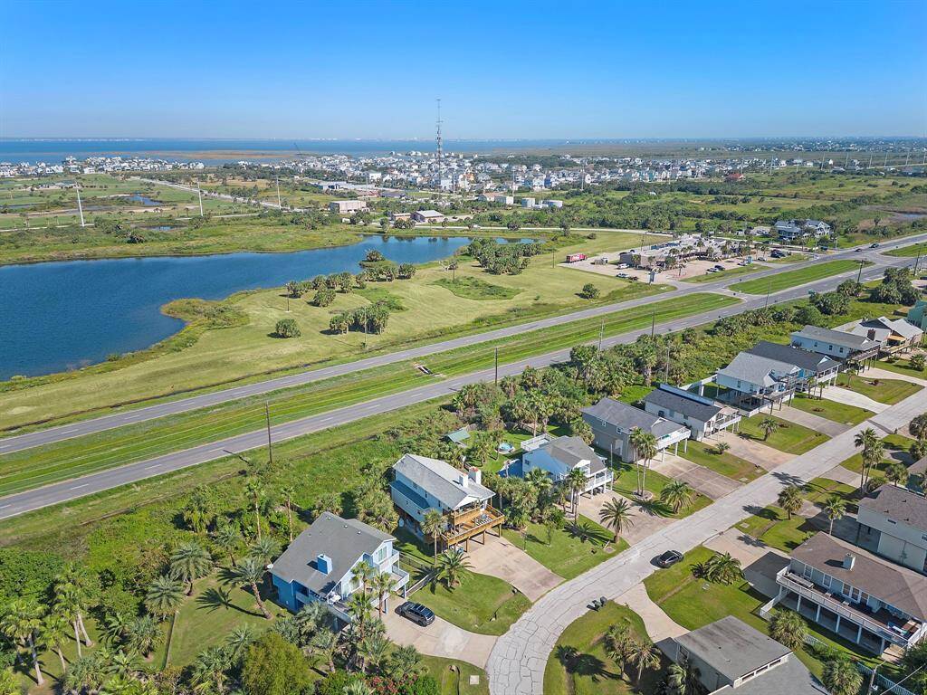 Expansive aerial view showing the property in context with nearby homes and the beautiful coastal waters just a short distance away.