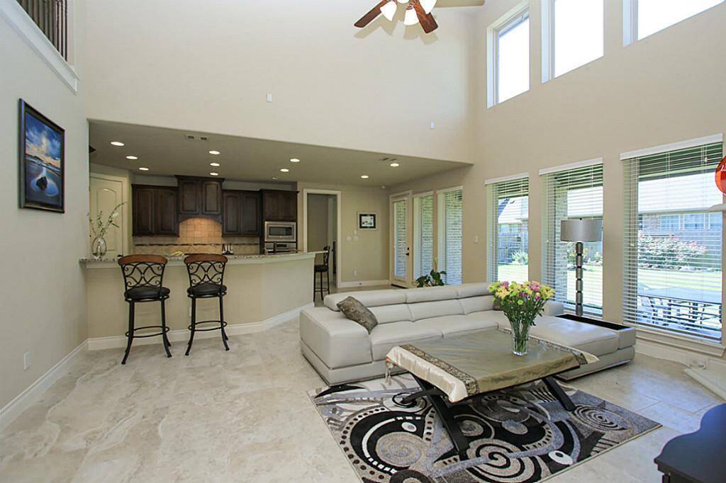 Soaring high ceiling in this bright family room with a whole wall of windows.