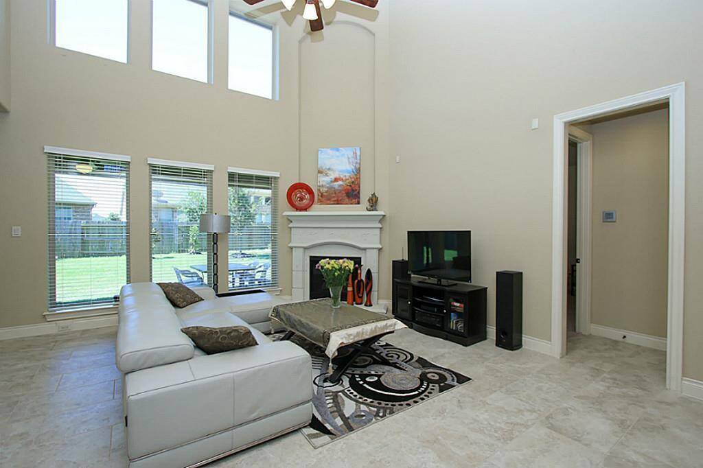 Family room with ceramic tile floor and cast stone fireplace flows into kitchen and breakfast  area.