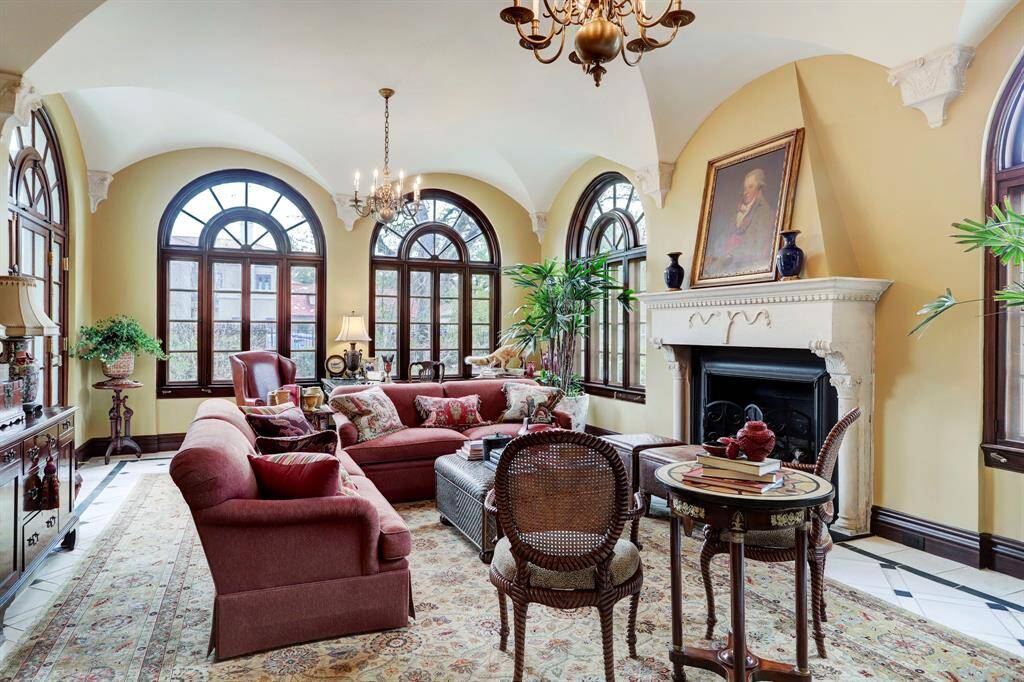 The restored Sun Parlor with groin vault ceiling, carved stonework, multiple arched windows, beautiful mantel and decorative stone floor is located in the southwest corner of the home. This room is drenched with sunlight from multiple arched windows and opens to a terrace that overlooks the pool.