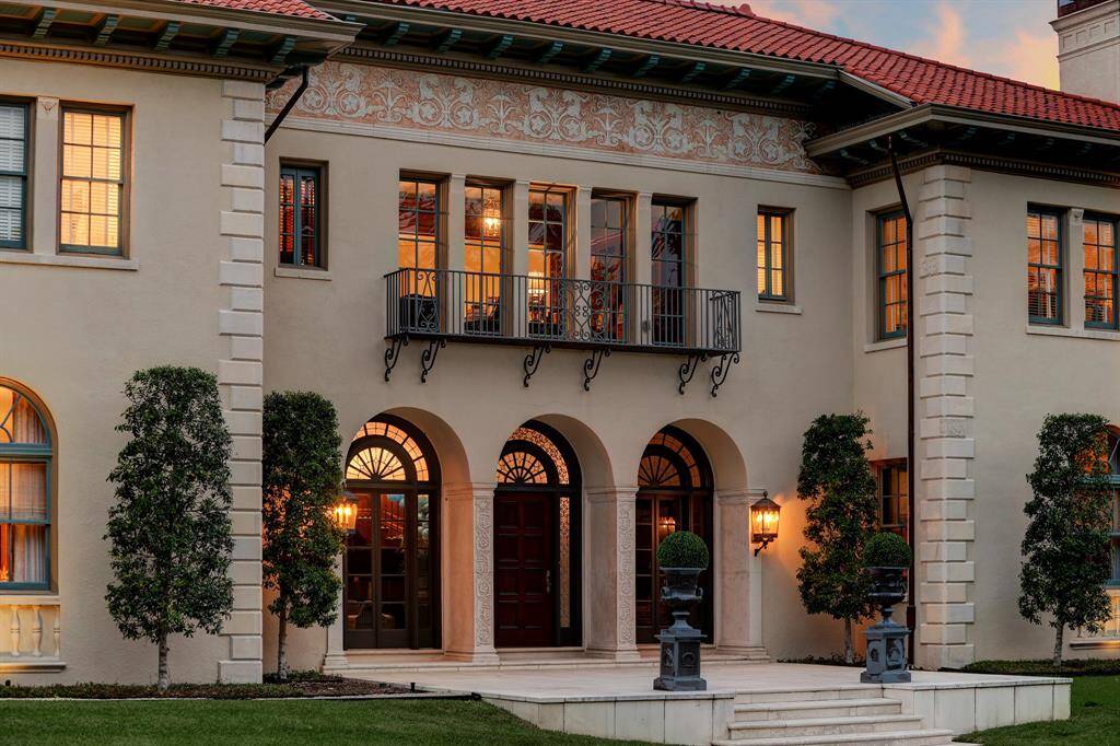 The ceremonious façade details a gorgeous frieze at the roof line with the most elaborate design. Rich in architectural details, this close-up view shows the triple arched entry, iron work, front door with fan light and ornamental ironwork.