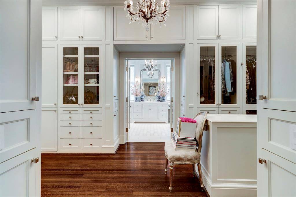 Located off grand hallway leading to the primary suite is the ladies dressing room/closet that opens to her bath.  There is an abundance of closets/cabinets and builtins with central island/folding counter. Just a peak of the dreamy bath beyond!