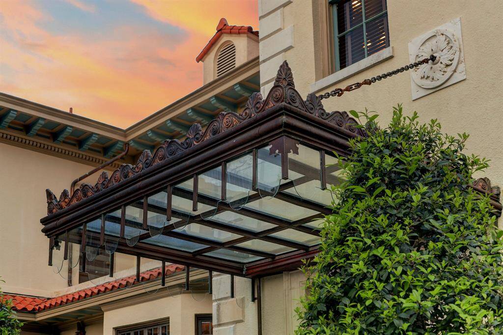 Restored iron and glass canopy attached to ornate stone medallions, located above the rear entrance to the home.
