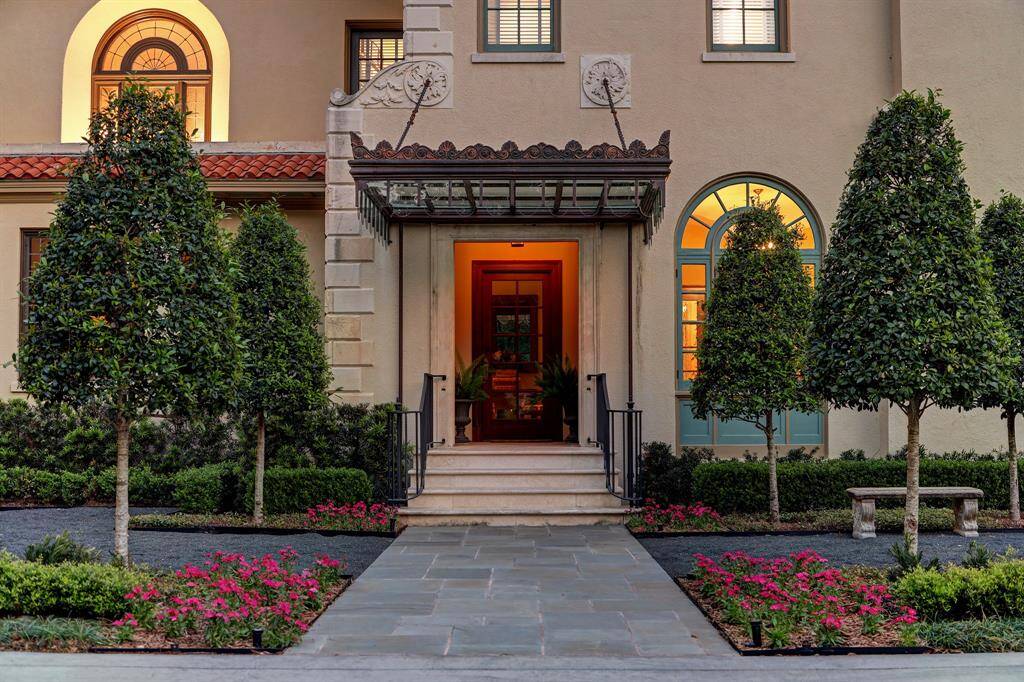 This architectural gem features imported woods, high ceilings, beautiful millwork, arched openings, carved stonework, restored elaborate glass canopy (pictured). This inviting rear entrance from motor court with tremendous architectural details, serves as an alternate and equally impressive entry to home framed by ornamental trees with refined hardscape.Great care was taken to restore the ornate metal and glass canopy.
