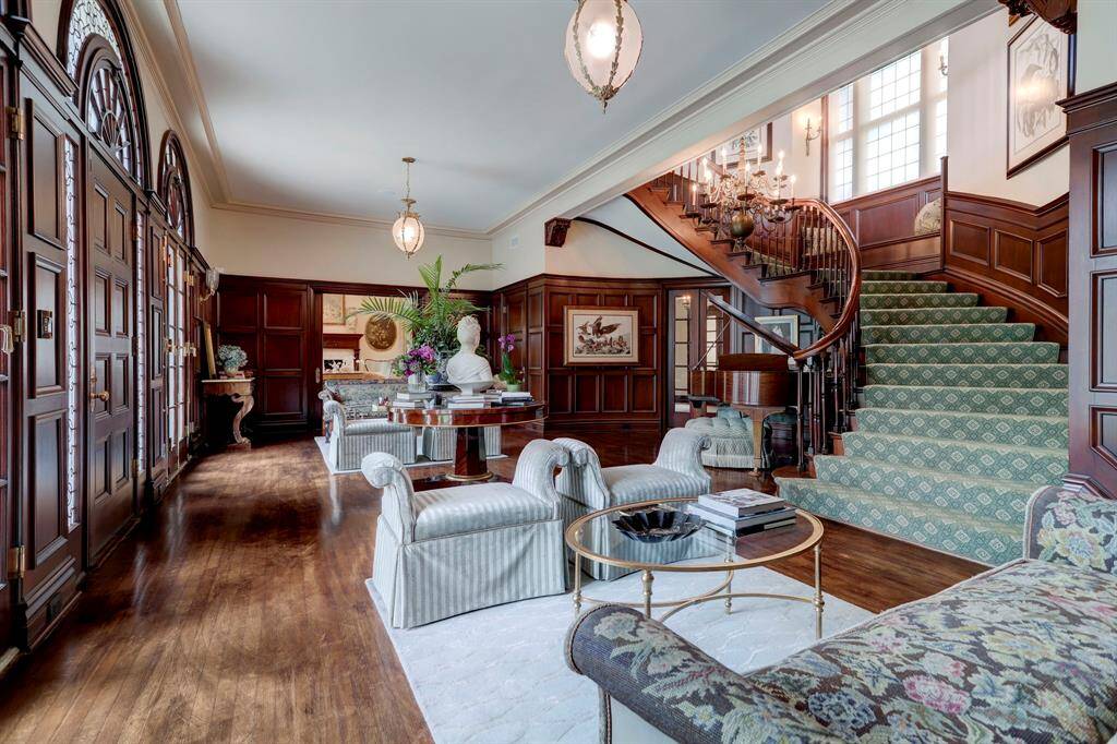 The expansive reception hall with handsome restored wood paneling, gleaming hardwoods, a graceful curving front staircase, and wide cased openings to the living and dining rooms, providing the most exceptional flow for grand entertaining.