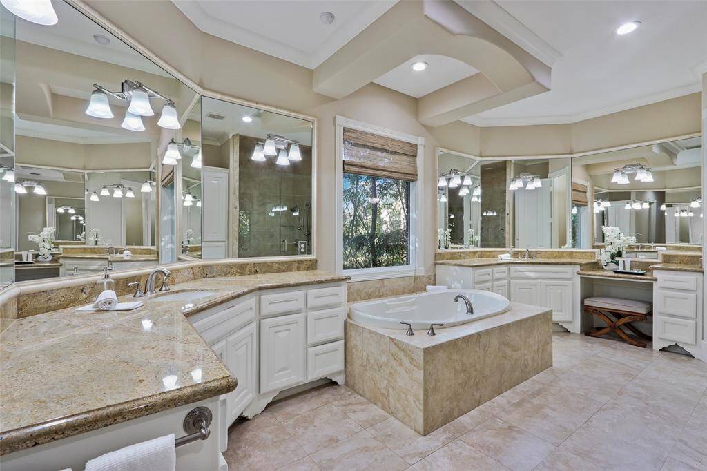 Huge primary bathroom with  dual sink areas, tub, shower with bench  and vanity.