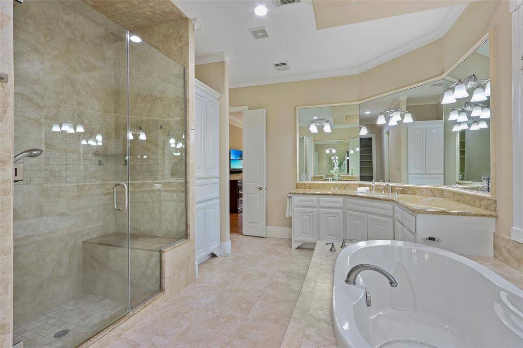Huge primary bathroom with  dual sink areas, tub, shower with bench  and vanity.
