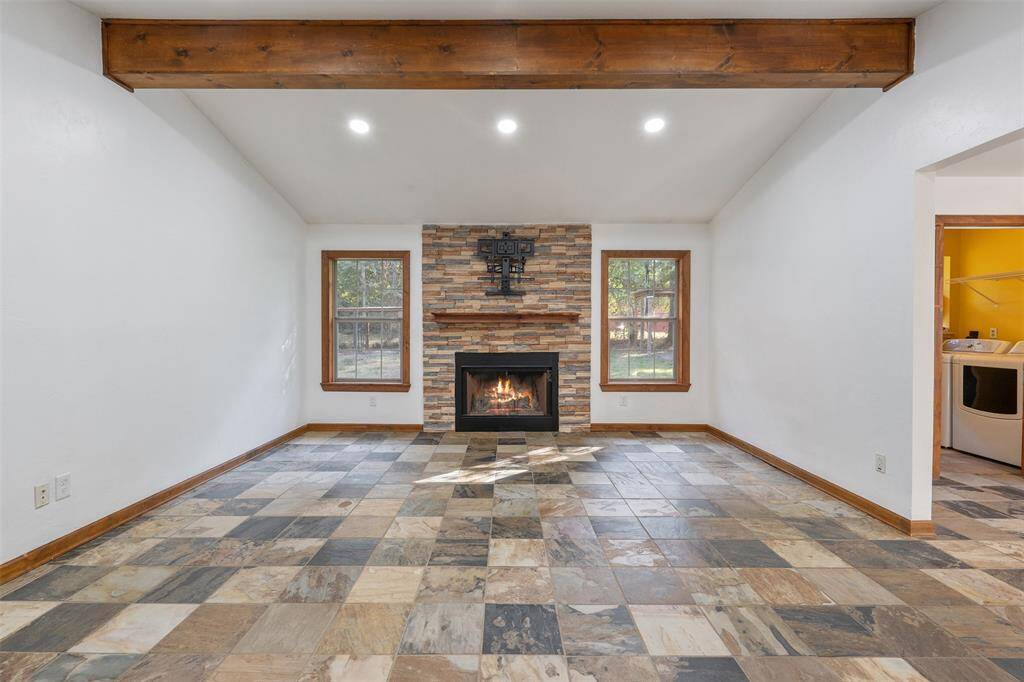 Gorgeous living room with fireplace and beautiful wood beam and wood trim around windows and baseboard.  This is a nice finish to the room. Virtual Fire in Fireplace
