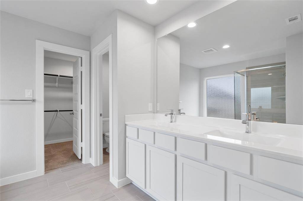 This large primary bath is spacious enough to share! With separate vanities, large closet space, plentiful cabinet and counter space, you are sure to have private area while sharing this bathroom!
