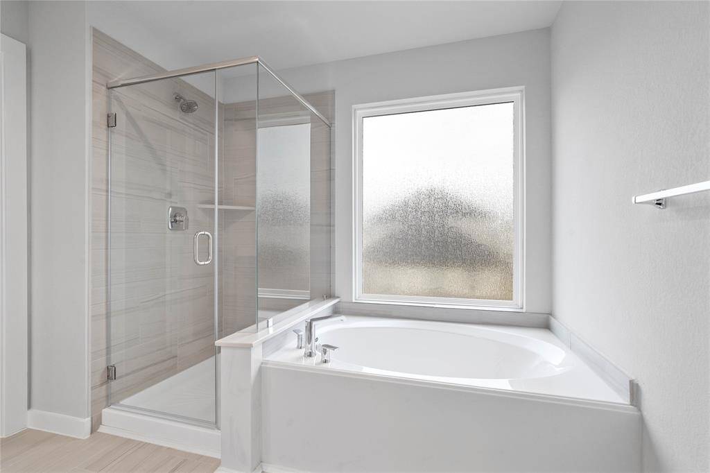 Additional view of the primary bathroom features walk-in shower with tile surround and separate garden tub.