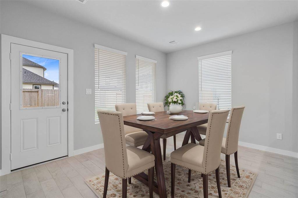 This lovely dining area is perfect for starting the day out on the right foot! This space showcases custom paint, recessed lighting, large windows with blinds adding to the ample natural light in the kitchen, and wood look tile flooring!