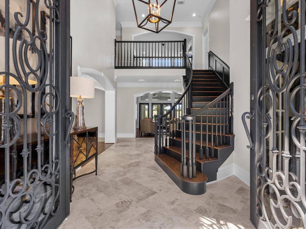 Welcome into an elegant foyer with a sweeping staircase and soaring ceilings.