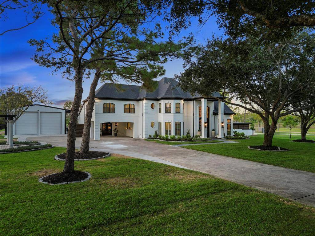 This is a spacious two-story home featuring a modern design with a white exterior and black accents, and an expansive driveway.