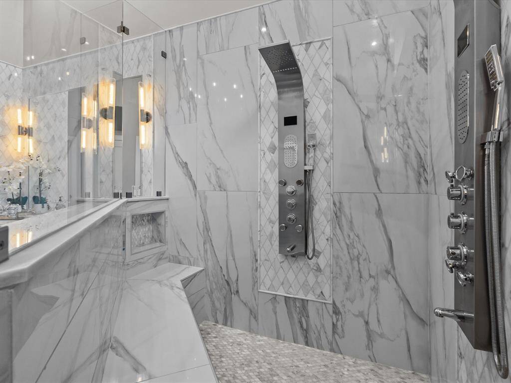 A luxurious walk-in shower equipped with a high-end, multi-jet panel system for a spa-like experience, and sleek, contemporary fixtures.