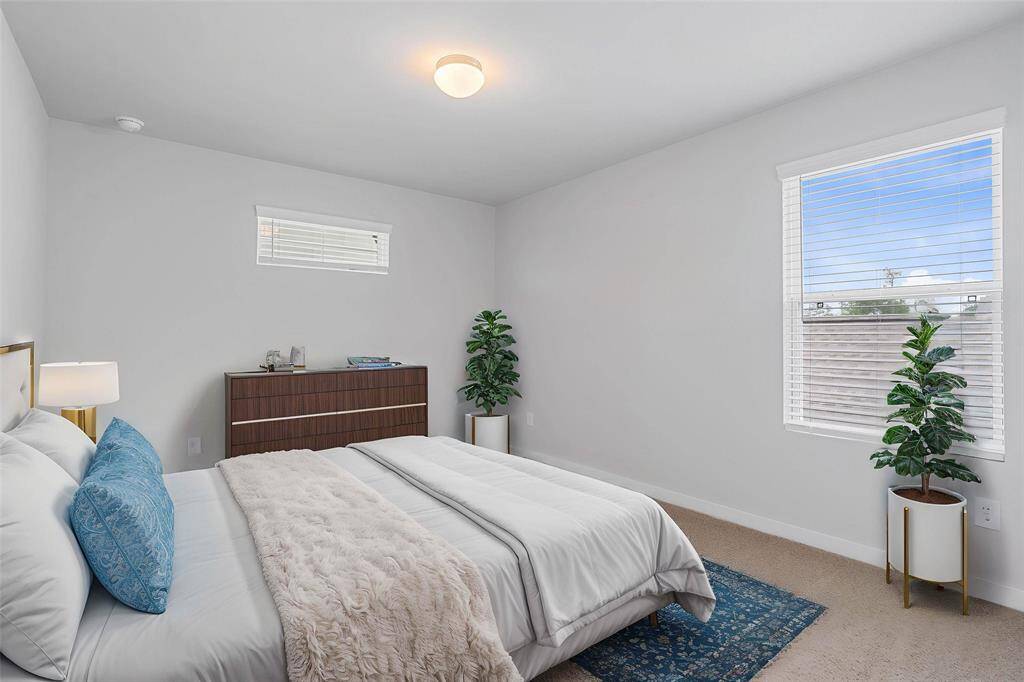 Secondary bedroom features plush carpet, custom paint, lighting, ample closet space, and large windows with privacy blinds!