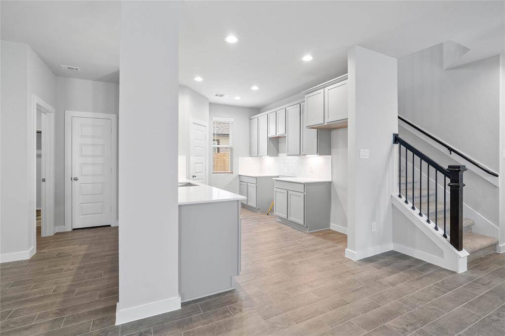 This stunning and spacious kitchen features high ceilings with recessed, pendant lighting, under cabinet lighting, stained wood cabinets, quartz countertops, modern tile backsplash, extended counter space for breakfast bar, and a walk-in pantry.