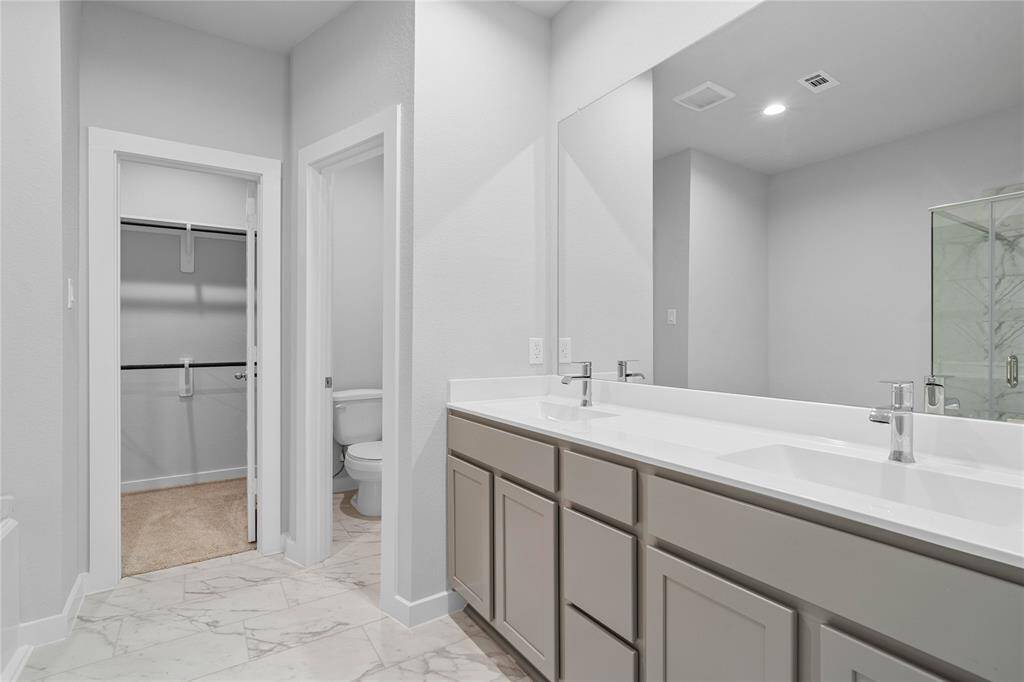 This primary bathroom is definitely move-in ready! Featuring stained cabinets with light countertops, dual vanities, spacious walk-in closet with shelving, high ceilings, custom paint, sleek and dark modern finishes.