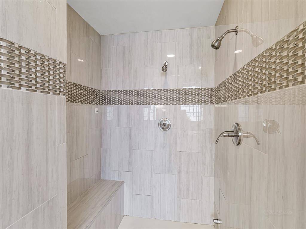 Walk-in shower with multiple shower heads.  and bench seating. Also serves as a steam room as well