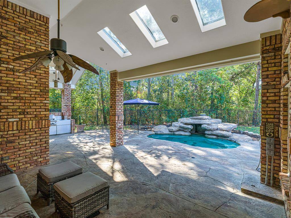 Covered patio with skylights have wonderful views of the sparkling pool with waterfall