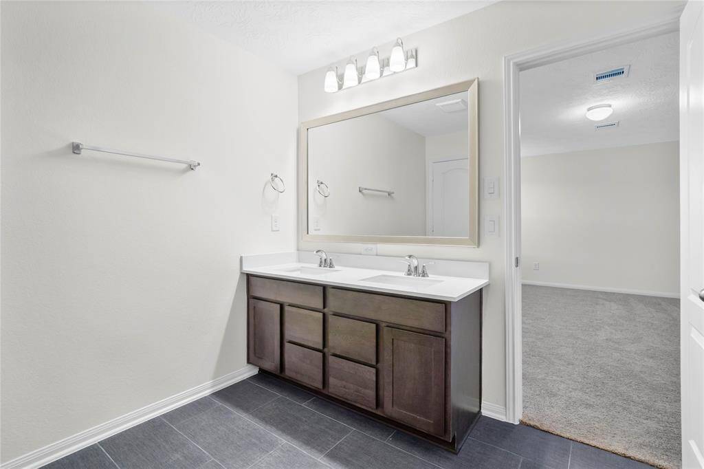 Wow! Look at this primary bathroom! Complete with cabinets and sleek light countertops, dual vanities, and large modern tile flooring. This bathroom is spectacular!