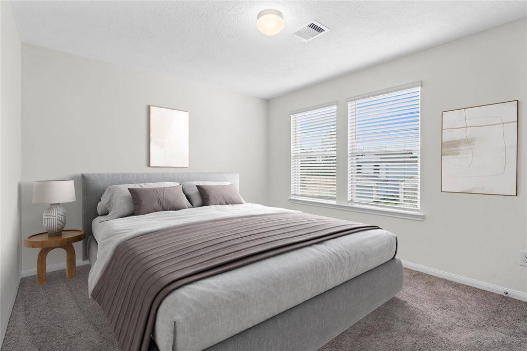 This secondary bedroom features high ceilings, custom paint, plush carpet, and large windows with privacy blinds!