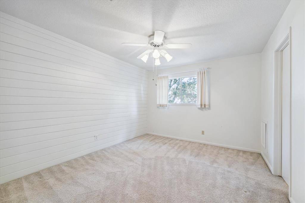 Charming upper-level bedroom featuring a shiplap feature wall and walk-in closet with private access to bathroom.