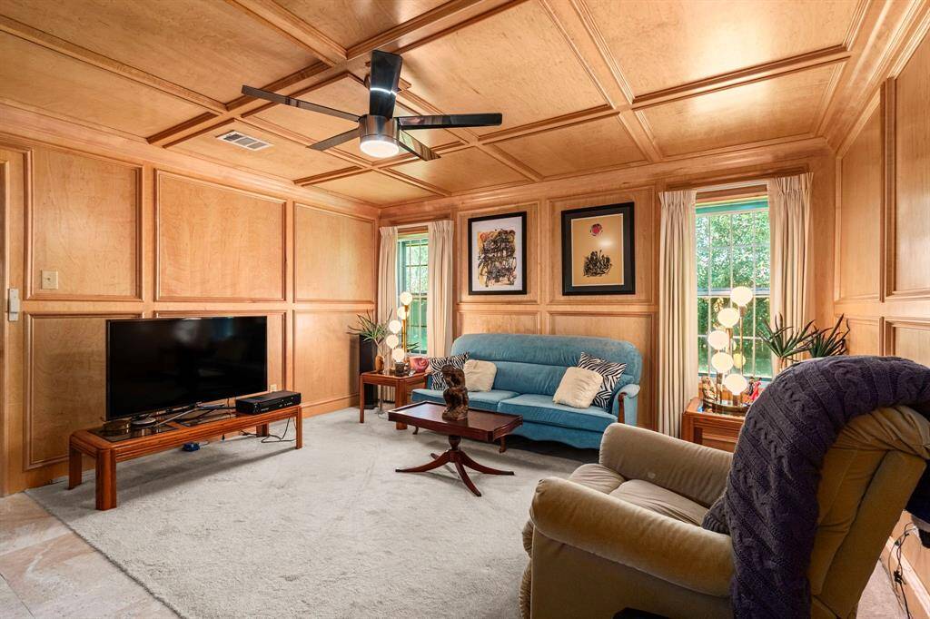 The spacious family room boasts solid wood block paneling and long windows with custom curtains.