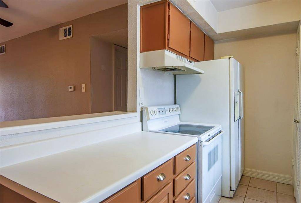 Galley kitchen with electric range and  breakfast bar. The stackable washer and dryer are across from fridge.
