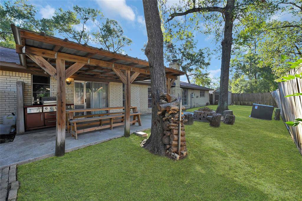 This is a spacious backyard featuring a covered patio. Mature trees provide shade and there's ample lawn space for activities.