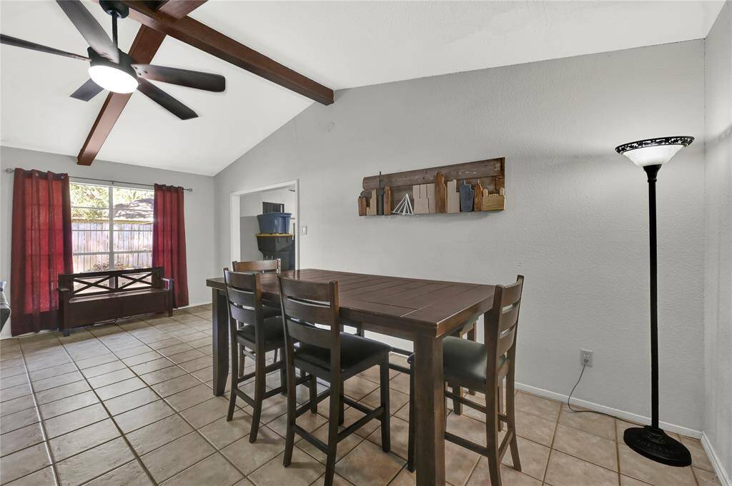 This is a cozy dining area featuring tile flooring, a high ceiling with a modern ceiling fan, natural light from large window.