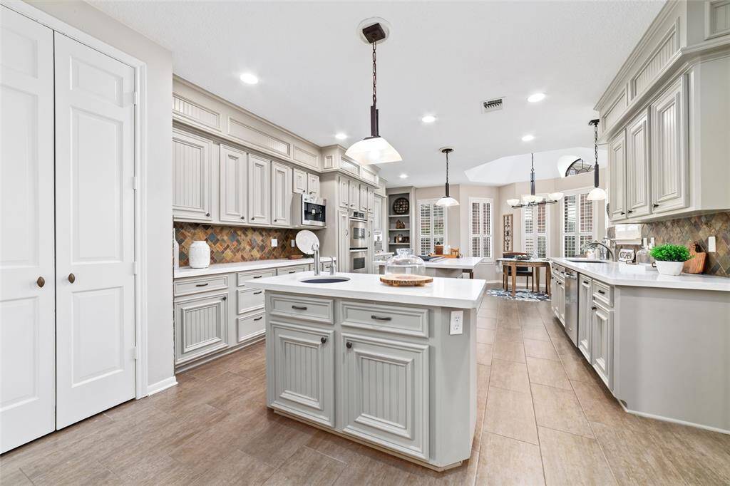Step into a chef's dream: a stunning updated kitchen boasting dual islands. The innovative layout includes a dedicated prep station with its own sink, streamlining your culinary workflow. Expansive quartz countertops and abundant cabinetry offer plentiful space for storage and food preparation, while elegant tile flooring adds a touch of sophistication to this functional masterpiece.