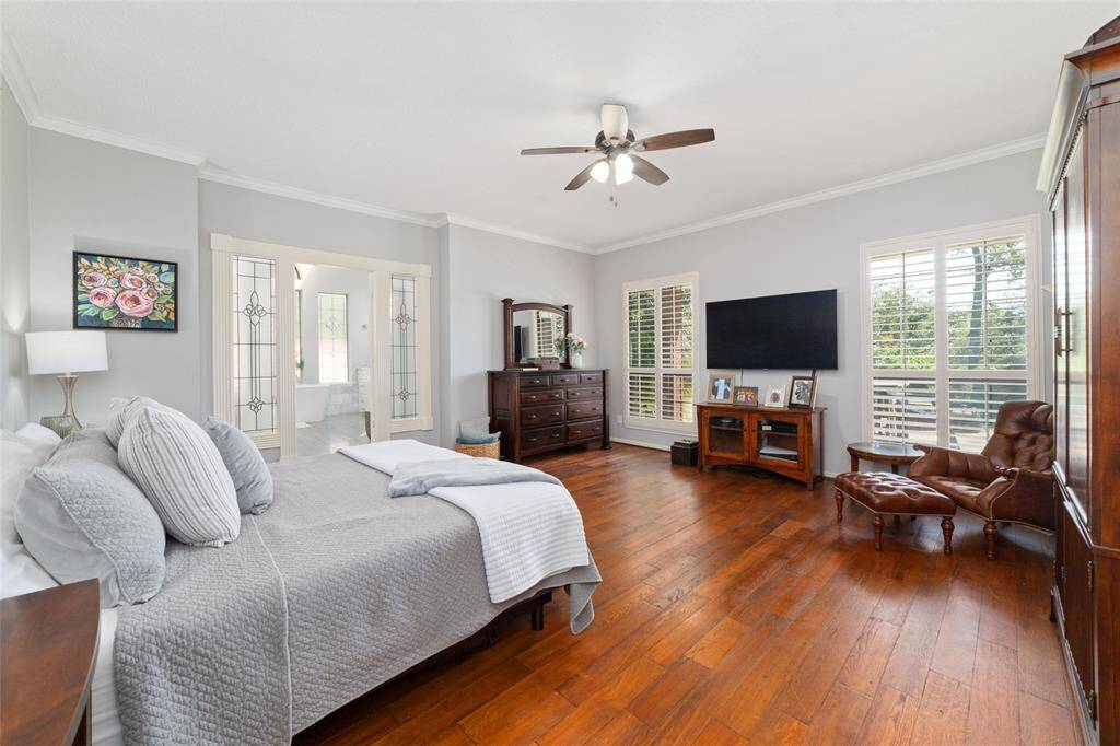 Retreat into this spacious primary bedroom featuring beautiful hardwood floors, large windows with plantation shutters and views of the breathtaking backyard. French doors lead to the spa-like ensuite bathroom.