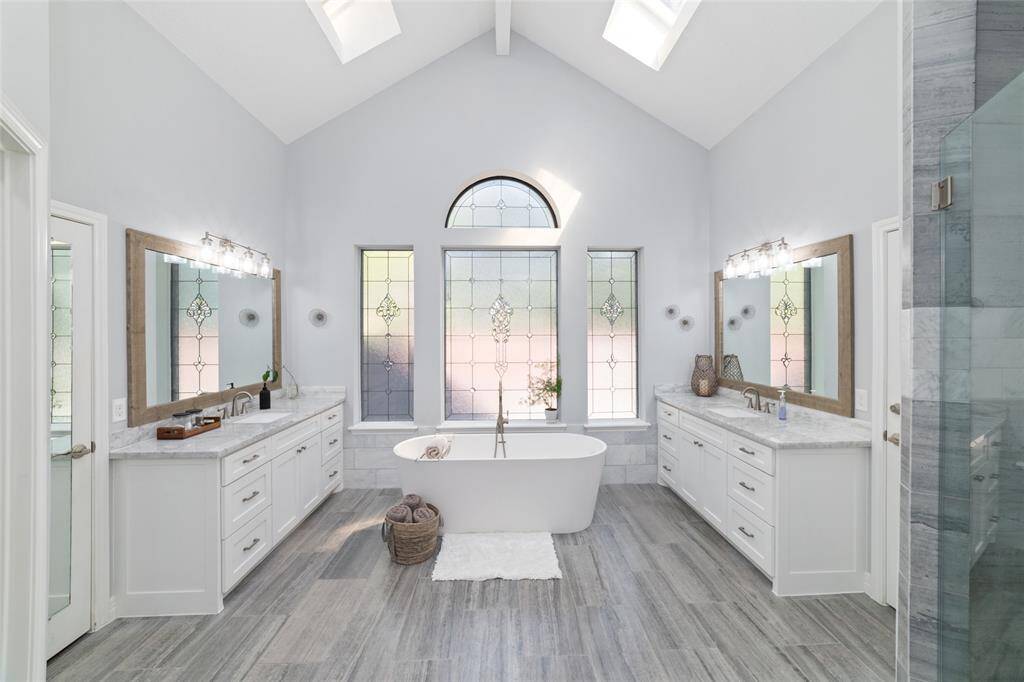 Welcome to paradise! The updated primary bathroom features a gorgeous freestanding tub, oversized shower, dual vanities and two large walk-in closets. High-end marble throughout, including the counters, flooring, shower surround and shower flooring. Notice the intricate decorative glass windows that bring in plenty of light while maintaining your privacy. High ceilings with skylights enhance the bright, airy feel.