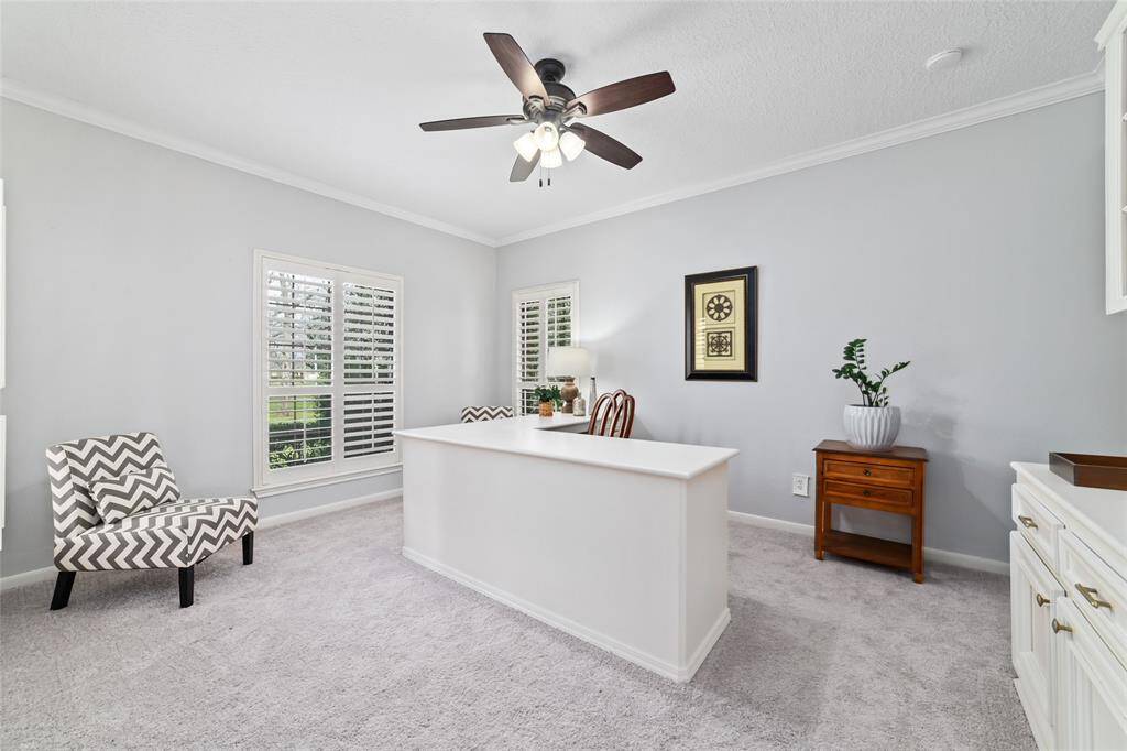 Large office located at the front of the home features new carpet, a built-in L-shaped desk and built-in cabinets with shelving. Plenty of natural light shines through the large windows with plantation shutters. Tucked away around the corner you'll find an additional closet area with cabinets and shelving.