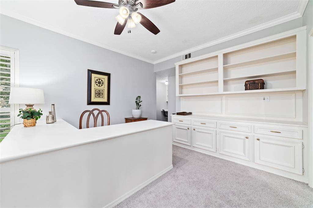 Another view of the spacious office featuring a wall of built-in cabinets and shelving.