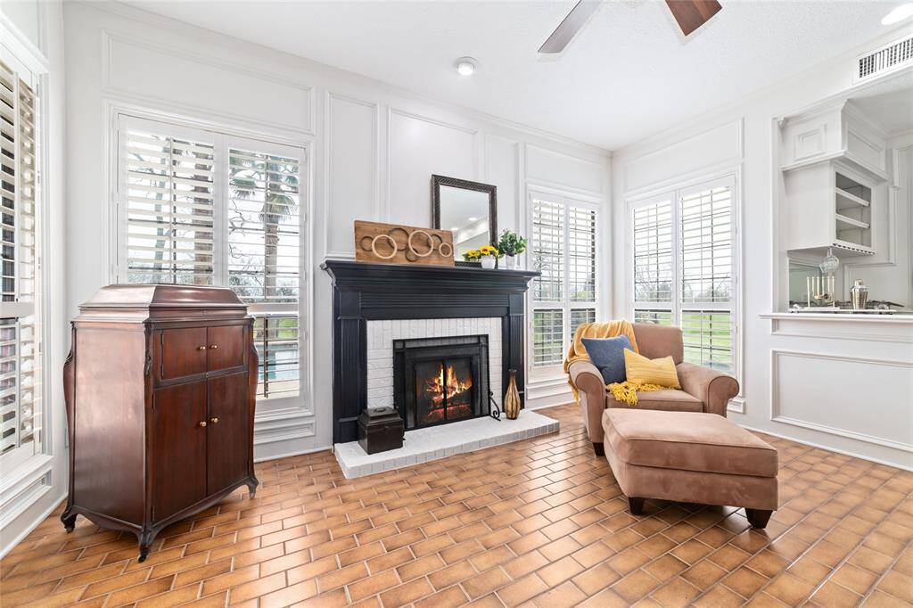 Spacious family room features a 1/2 bathroom, charming brick-look tile flooring, wall-to-wall built-in cabinets and shelving, wet bar and fireplace. This is the perfect spot for entertaining guests, as they can easily roam from poolside to the air conditioned comfort of this versatile space.