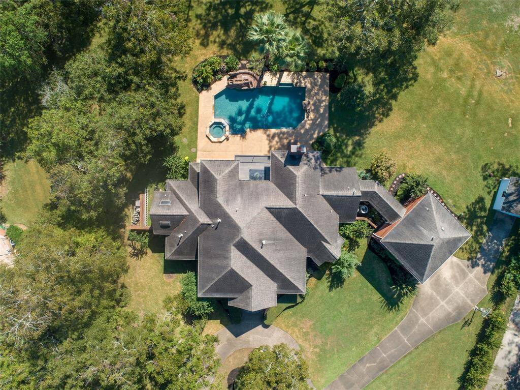 Aerial view of this spacious 2.5 acre property featuring a large swimming pool surrounded by lush greenery and a well-maintained lawn, offering privacy and a luxurious outdoor living space.