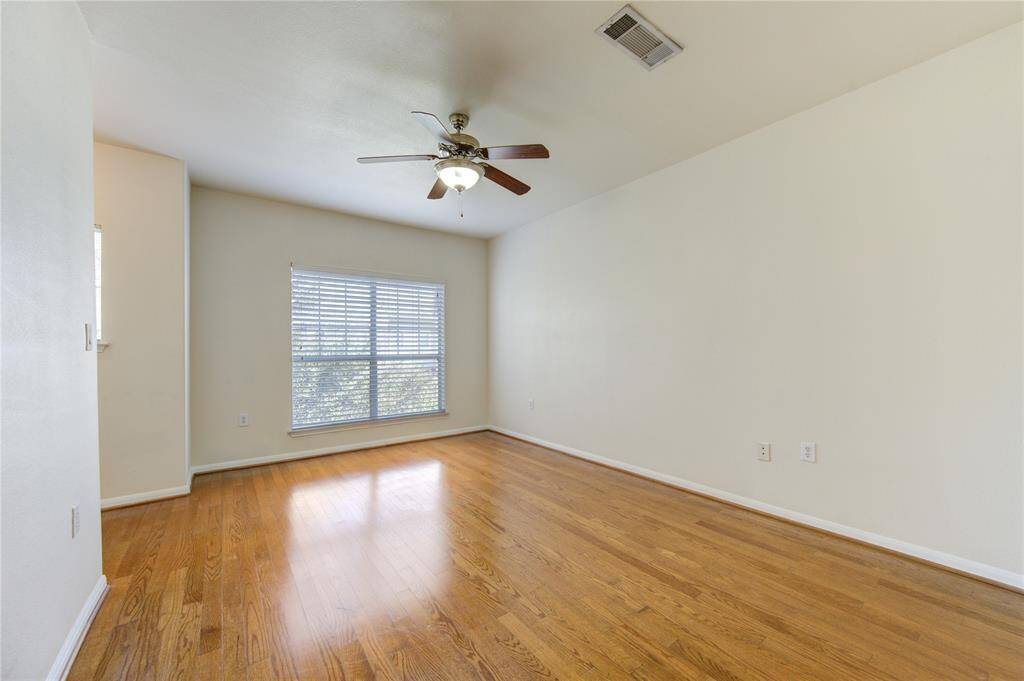 Bright bedroom featuring hardwood  floors & a large window.