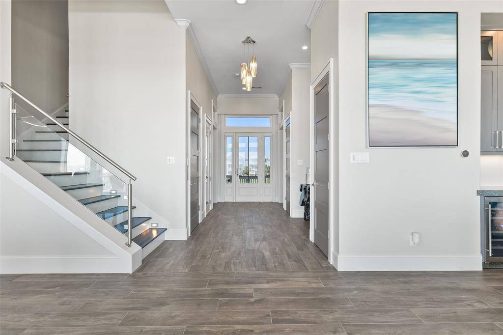 Welcome to this elegant entryway, a beautifully designed hallway that seamlessly connects the downstairs bedrooms, utility room, living area, elevator, and stairs. The stunning wood-paneled elevator, with a 950 lb capacity, offers ease of access, while real wood stairs, illuminated by LED stair lights, provide a warm, inviting path through this climate-controlled space.
