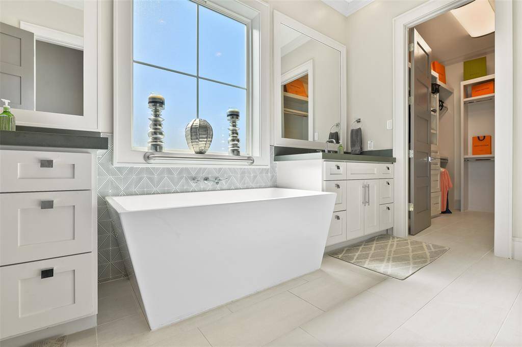 The primary bathroom boasts designer tile and a sleek, modern rectangular freestanding tub, creating a spa-like atmosphere. It also features a spacious walk-in closet, providing ample storage in this luxurious retreat.