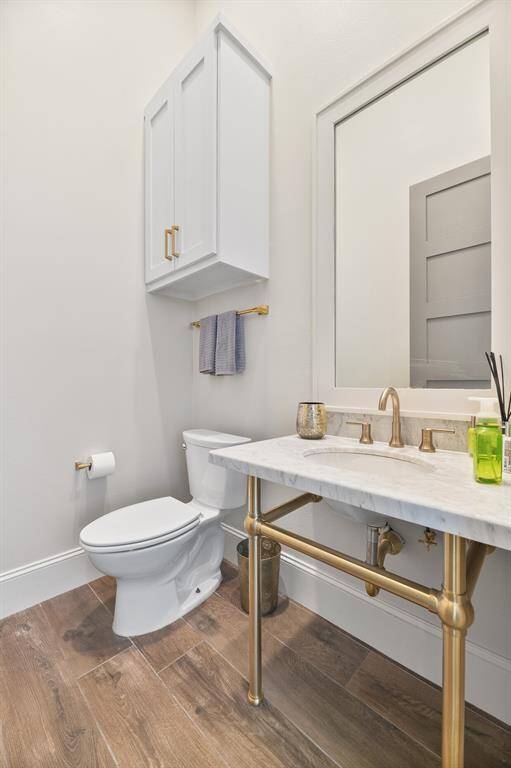 This elegant half bath features a framed vanity mirror, sleek quartz countertops, and a modern undermount trench-style sink. A perfect blend of luxury and style, it adds a refined touch to this coastal home.